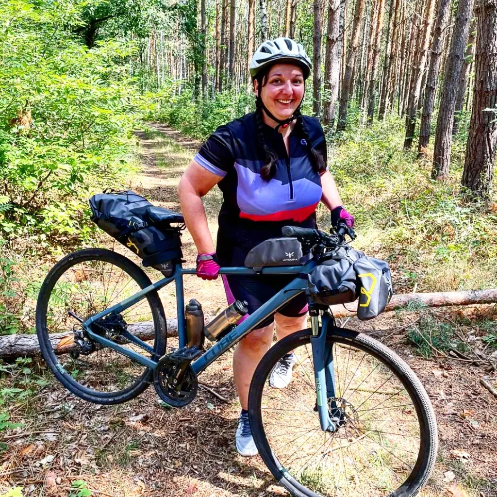 Fahrrad wird über Baumstamm im Wald gehoben.