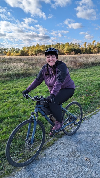 Frau fährt im Herbst mit Fahrrad über Feld