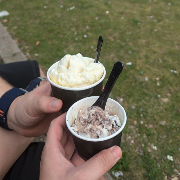 Zwei Menschen halten Eisbecher auf Wiese