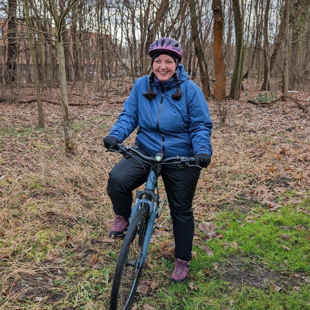 Radfahrerin bei kalten Temperaturen mit Wintersachen im Wald