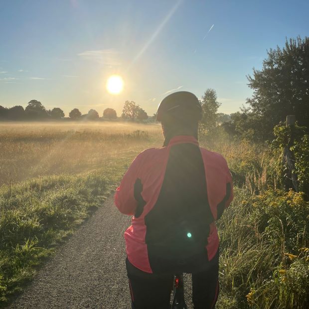 Radfahrerin bei Sonennaufgang im Herbstnebel