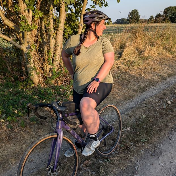 Radfahren während der Periode in bequemer Kleidung. Frau auf Fahrrad im Sonnenuntergang und T Shirt