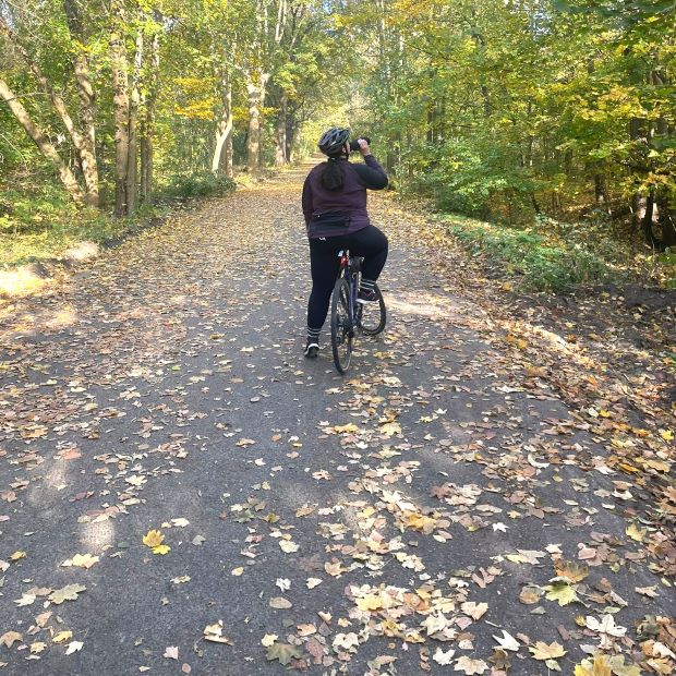 Radfahren während der Periode. Frau trinkt Wasser auf Fahrrad.