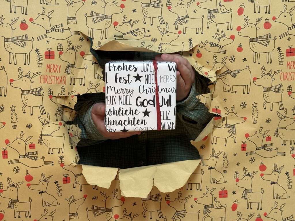 Geschenkideen Jessica Riedel hält Geschenk durch Geschenkpapier