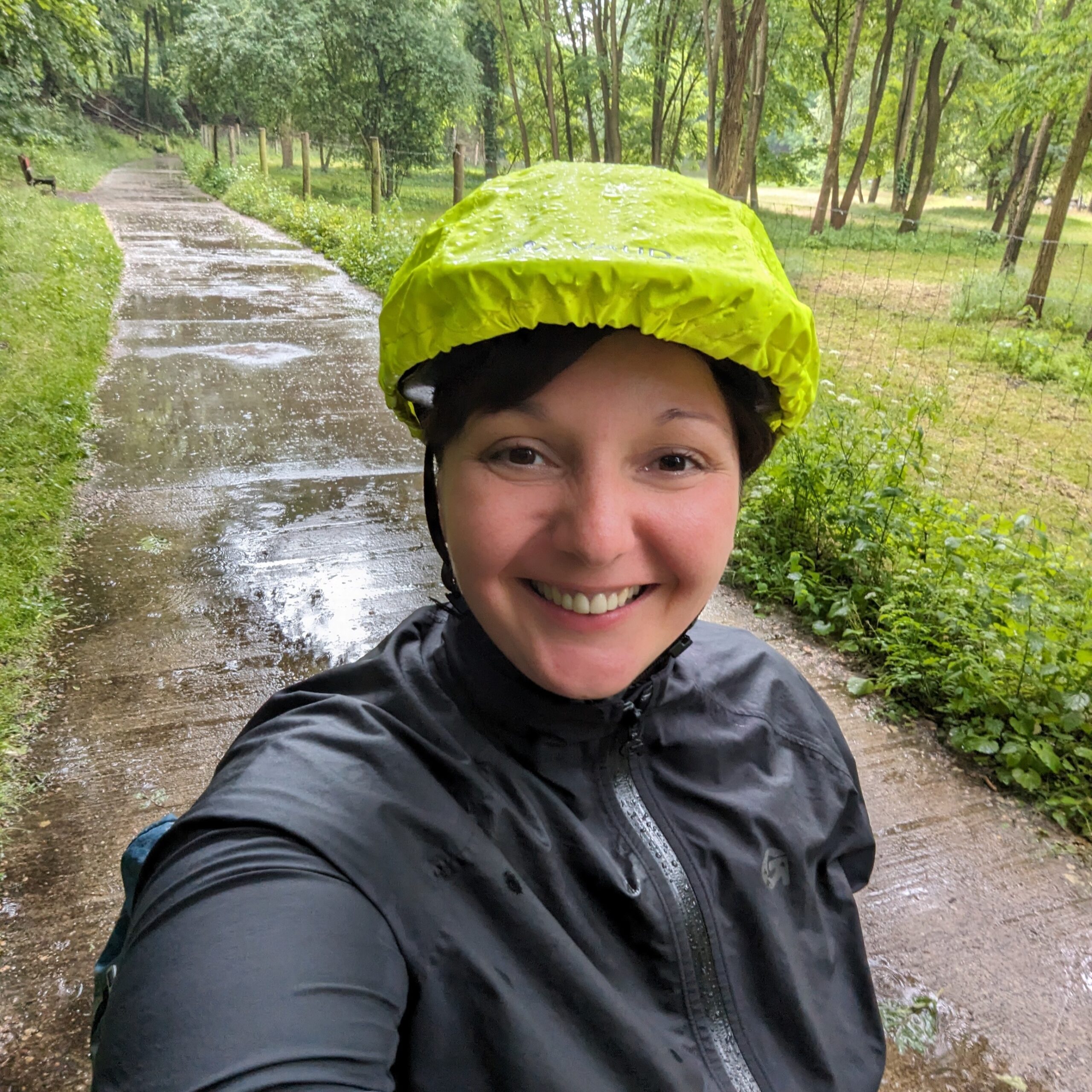 Jersey Cycles. Frau auf Fahrrad bei Regenwetter. Regenschutz für Helm