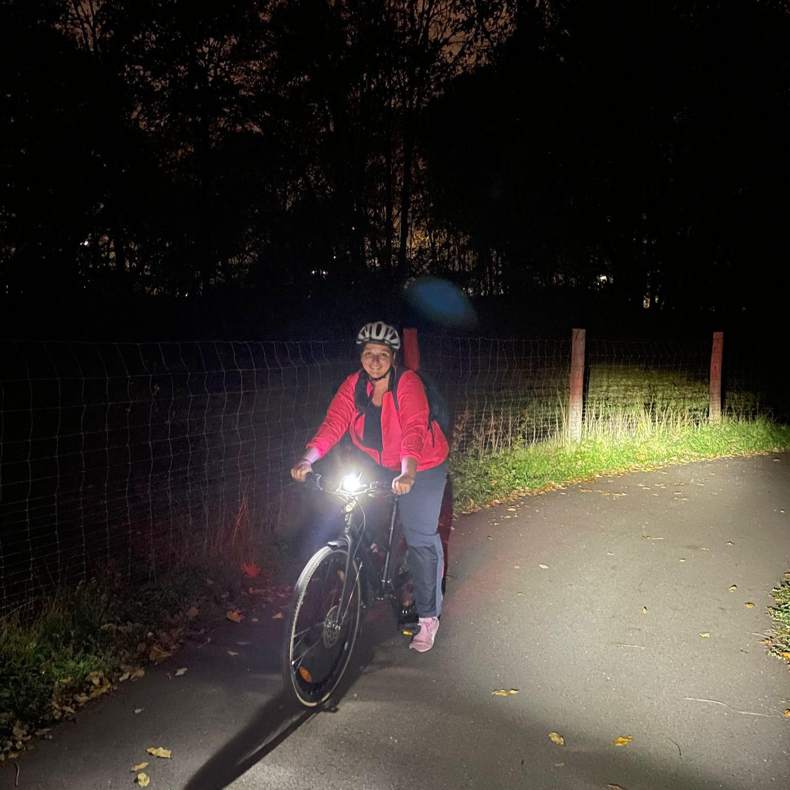 pendeln mit dem rad im dunklen. frau auf stadtrad mit lampen und heller kleidung