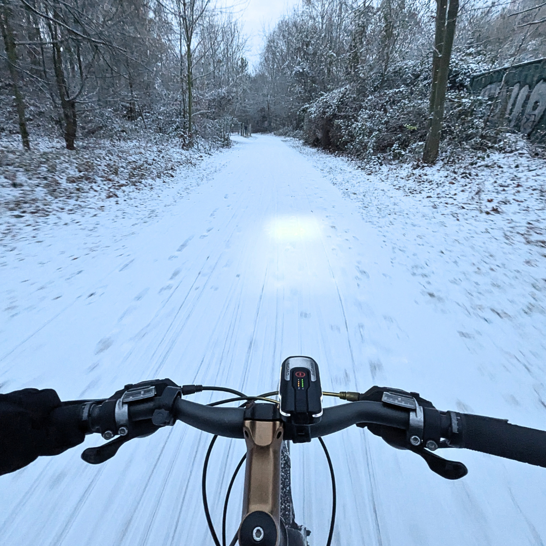 Blick vom Fahrradlenker auf schneebedeckte Fahrbahn